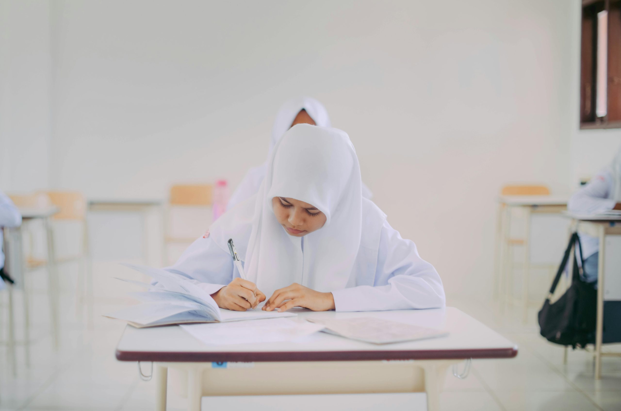 Muslim student focused on writing during class in Indonesia.