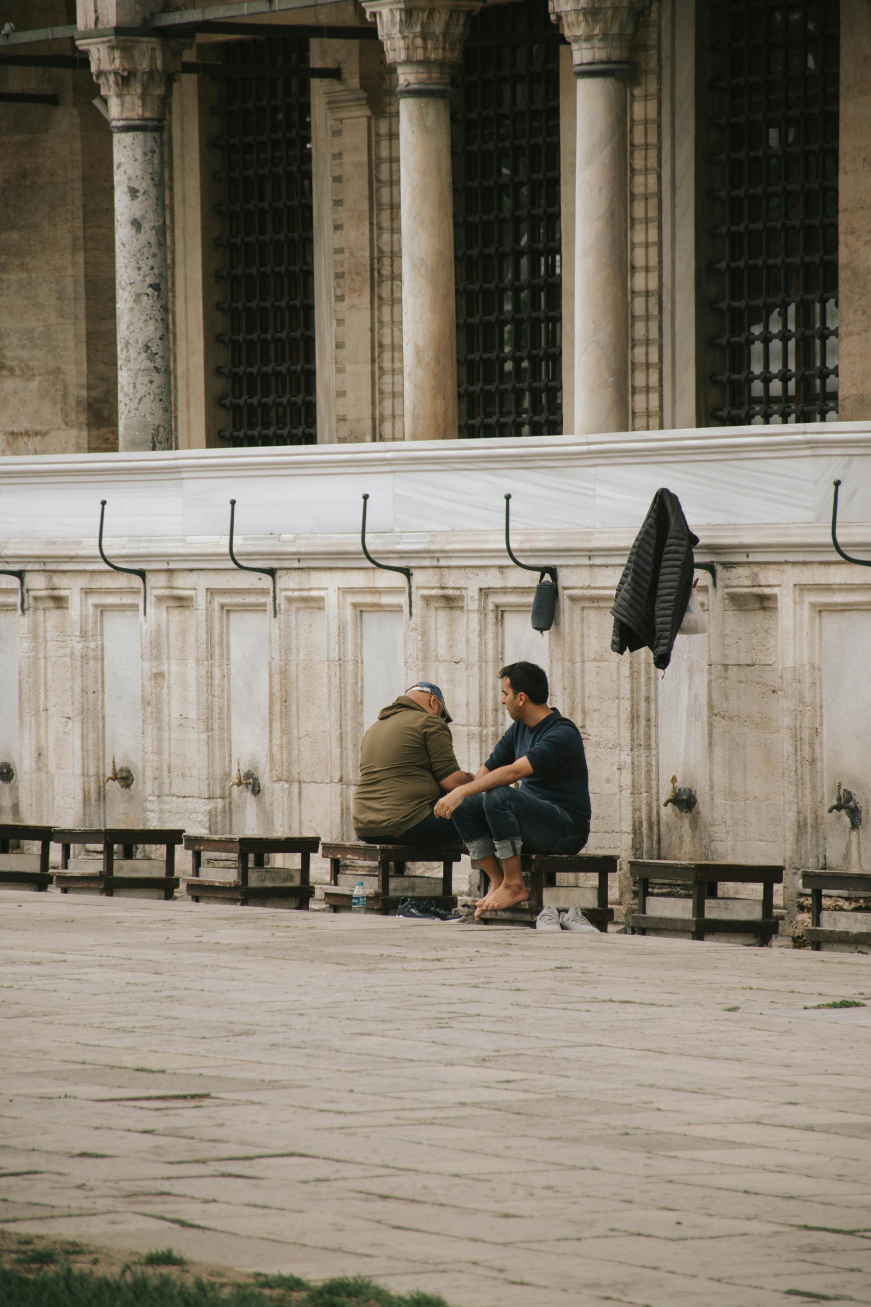 Two men perform ablution at Istanbul's iconic Suleymaniye Mosque, capturing traditional Islamic practices.